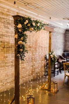 the wedding arch is decorated with white roses and greenery for an elegant touch to the reception space