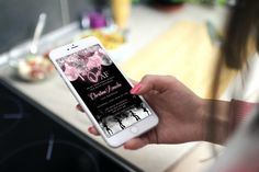 a person holding an iphone in their hand and touching the screen with her finger, on a kitchen countertop