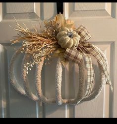 a wreath hanging on the front door decorated with fall leaves and dried wheat for decoration