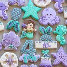 decorated cookies are arranged in the shape of mermaids and seahorses for a birthday party