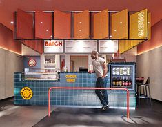 a man standing in front of a blue and orange counter with sodas on it