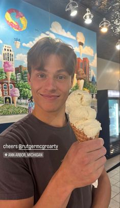 a man holding an ice cream cone in his right hand and smiling at the camera