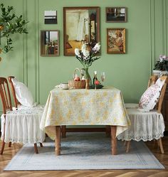 a dining room with green walls and white table cloths on the table, two chairs