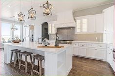 a large kitchen with white cabinets and counter tops next to an island in the middle