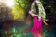 a woman in a pink dress is floating on the water with flowers around her neck