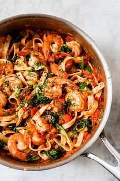 pasta with shrimp, spinach and tomato sauce in a pan