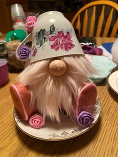 a close up of a plate with a toy gnome on it's head and flowers