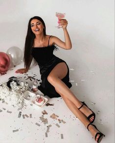 a woman sitting on the floor with confetti and balloons in front of her