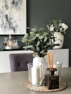 a table topped with candles and vases filled with greenery