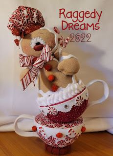 a teddy bear sitting on top of a coffee cup in front of a sign that reads raggedy dreams