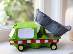 a green toy truck sitting on top of a window sill next to a potted plant