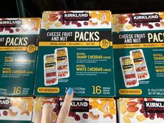 several packages of cheese fruit and nut snacks for sale in a grocery store, with a hand pointing at them