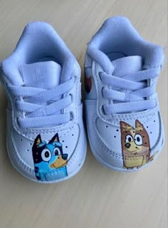 a pair of shoes with cartoon characters painted on the upper part of each shoe, sitting on a wooden surface