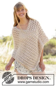 a woman wearing a crocheted ponchy standing on the beach