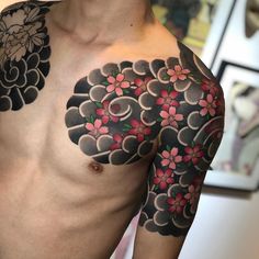 a man with tattoos on his chest and shoulder is wearing a flowered tattoo design