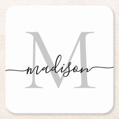 the word madison in black ink on a white beverage coaster with a monogrammed letter