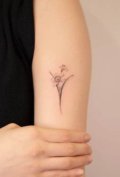 a woman's arm with a small flower tattoo on the left side of her arm