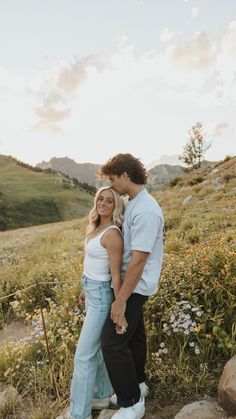 a man and woman standing on top of a hill