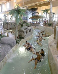 many people are swimming in the water at an indoor pool with slides and waterfalls