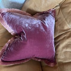 a purple pillow sitting on top of a brown couch