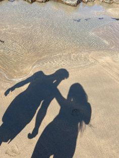 the shadow of two people standing in the sand