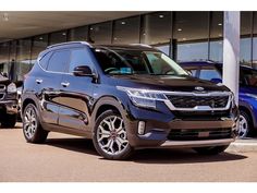 the front view of a black suv parked in front of a building with other cars