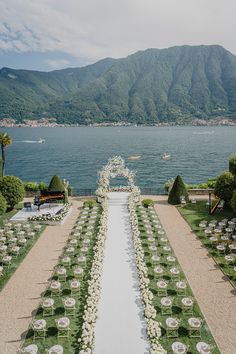 an outdoor wedding setup with white flowers and greenery on the lawn by the water