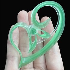 a hand holding a green heart shaped brooch