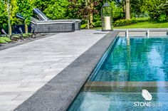 an empty swimming pool with lounge chairs and trees in the backgroung area