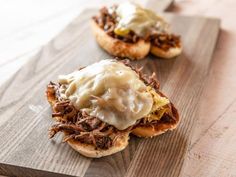 two pulled pork sandwiches on a wooden cutting board