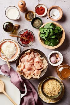 an assortment of food is laid out on a table with utensils and sauces