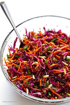 a bowl filled with red cabbage, carrots and sprinkles next to a spoon