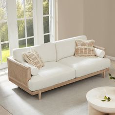 a white couch sitting in front of a window next to a table with flowers on it