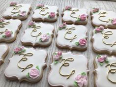 many decorated cookies with pink and white frosting are arranged on a wooden table top