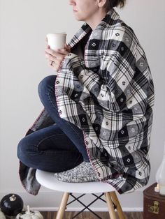 a woman sitting on top of a chair holding a cup