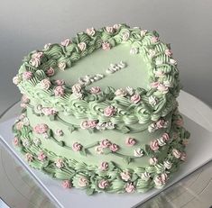 a heart shaped cake with pink and green frosting on a platter next to a record player