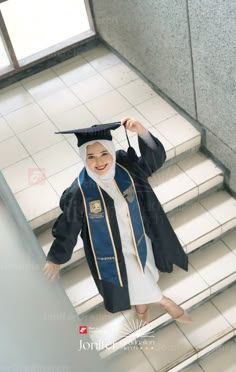 a woman in a graduation cap and gown is walking down the stairs