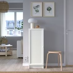 a white cabinet sitting in the middle of a living room next to a chair and table