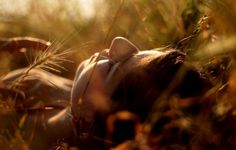 a woman laying down in the grass with her eyes closed and head resting on her back