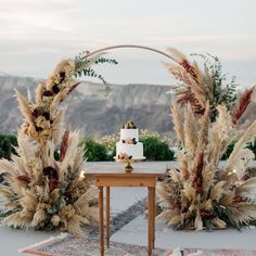 a wedding cake sitting on top of a wooden table next to tall pamodia