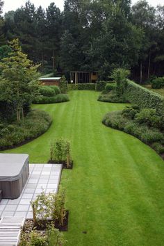 an aerial view of a large green lawn and garden area with trees in the background