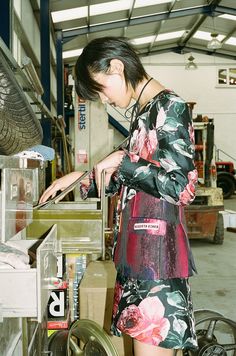 a woman in a floral print dress is working on an assembly line at a factory