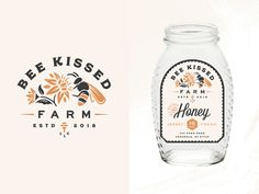 a glass jar filled with honey sitting on top of a white table next to a label for bee kissed farm