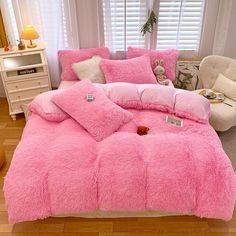 a bed covered in pink fluffy blankets and pillows