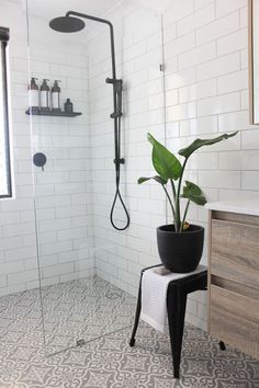 a white tiled bathroom with a plant in the corner