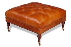 a brown leather ottoman sitting on top of a wooden table