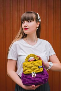 a woman holding a crocheted purse in her hands