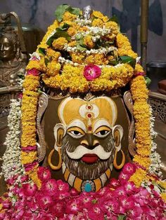 an elaborately decorated statue with flowers around it's head and eyes on display