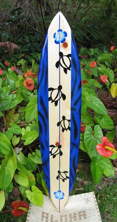 a blue and white surfboard sitting on top of a wooden stand next to flowers