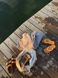 a pair of flip flops are sitting on a wooden dock next to a bag